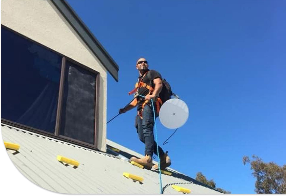 Technician installing satellite dish antenna on residential rooftop